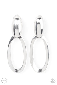 An asymmetrical silver oval hinges from the bottom of a spherical silver oval fitting, resulting in a radiant lure. Earring attaches to a standard clip-on fitting.  Sold as one pair of clip-on earrings.