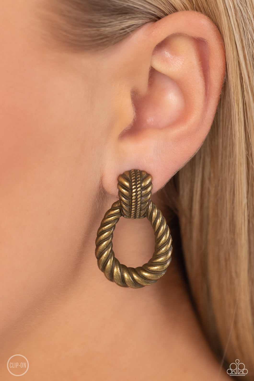 Featuring twisted ropelike texture, an antiqued loop attaches to a studded brass fitting for a rustic flair. Earring attaches to a standard clip-on earring.  Sold as one pair of clip-on earrings.