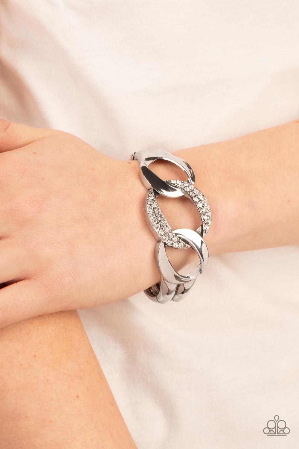 A trio of rounded square silver links, featuring a hammered texture, interlock into an unapologetic display. The centermost link is dotted with glassy rhinestones, creating a sparkly fashion around the wrist. Features a hinged closure.  Sold as one individual bracelet.
