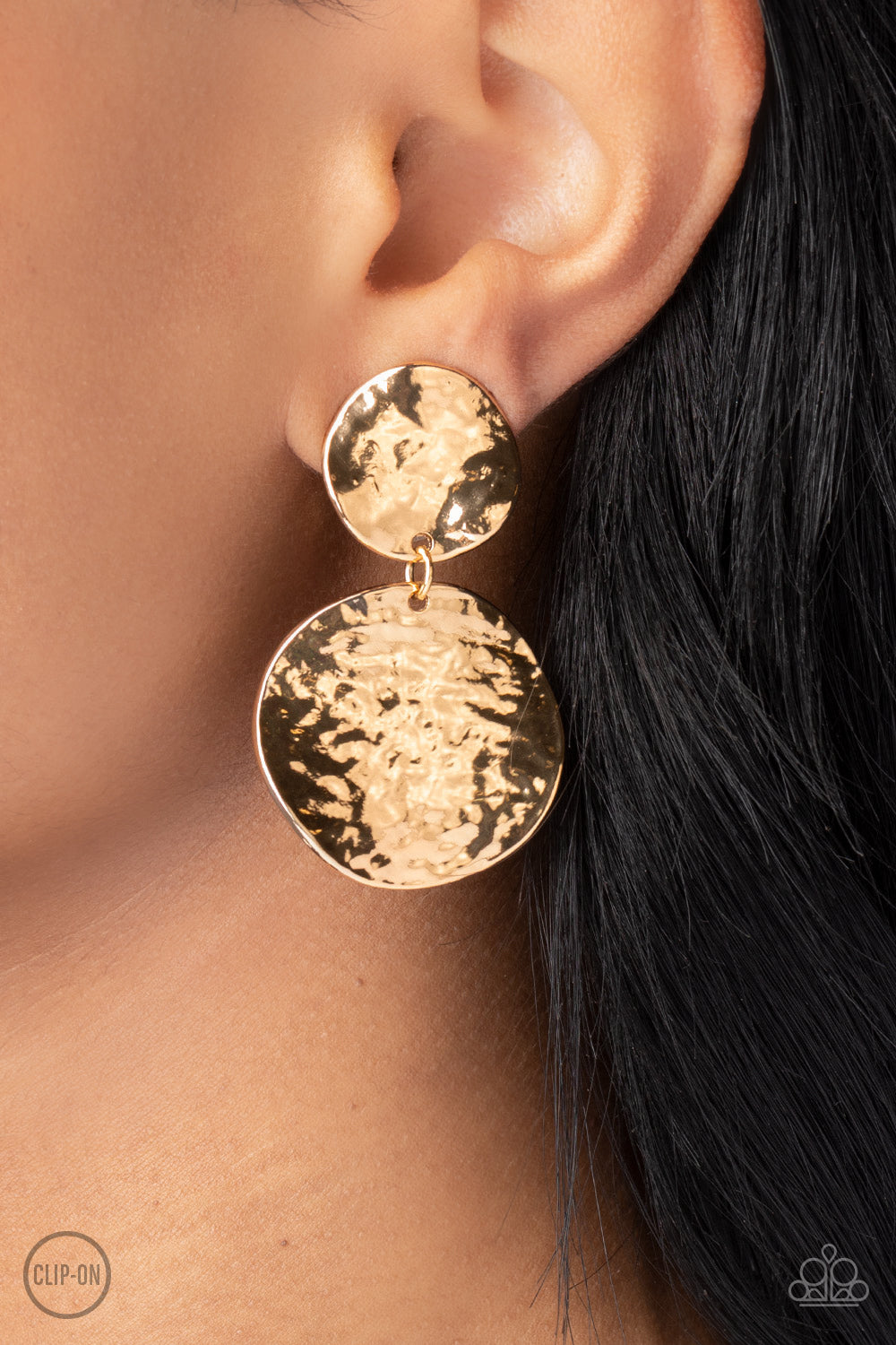 Hammered with high-sheen texture, warped gold discs delicately link into a bold monochromatic statement piece. Earring attaches to a standard clip-on fitting.  Sold as one pair of clip-on earrings.
