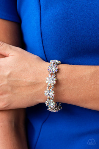 Separated by pairs of dainty silver beads, iridescent rhinestone dotted petals bloom from oversized white rhinestone centers along stretchy bands around the wrist for a flirtatious floral fashion. Due to its prismatic palette, color may vary.  Sold as one individual bracelet.