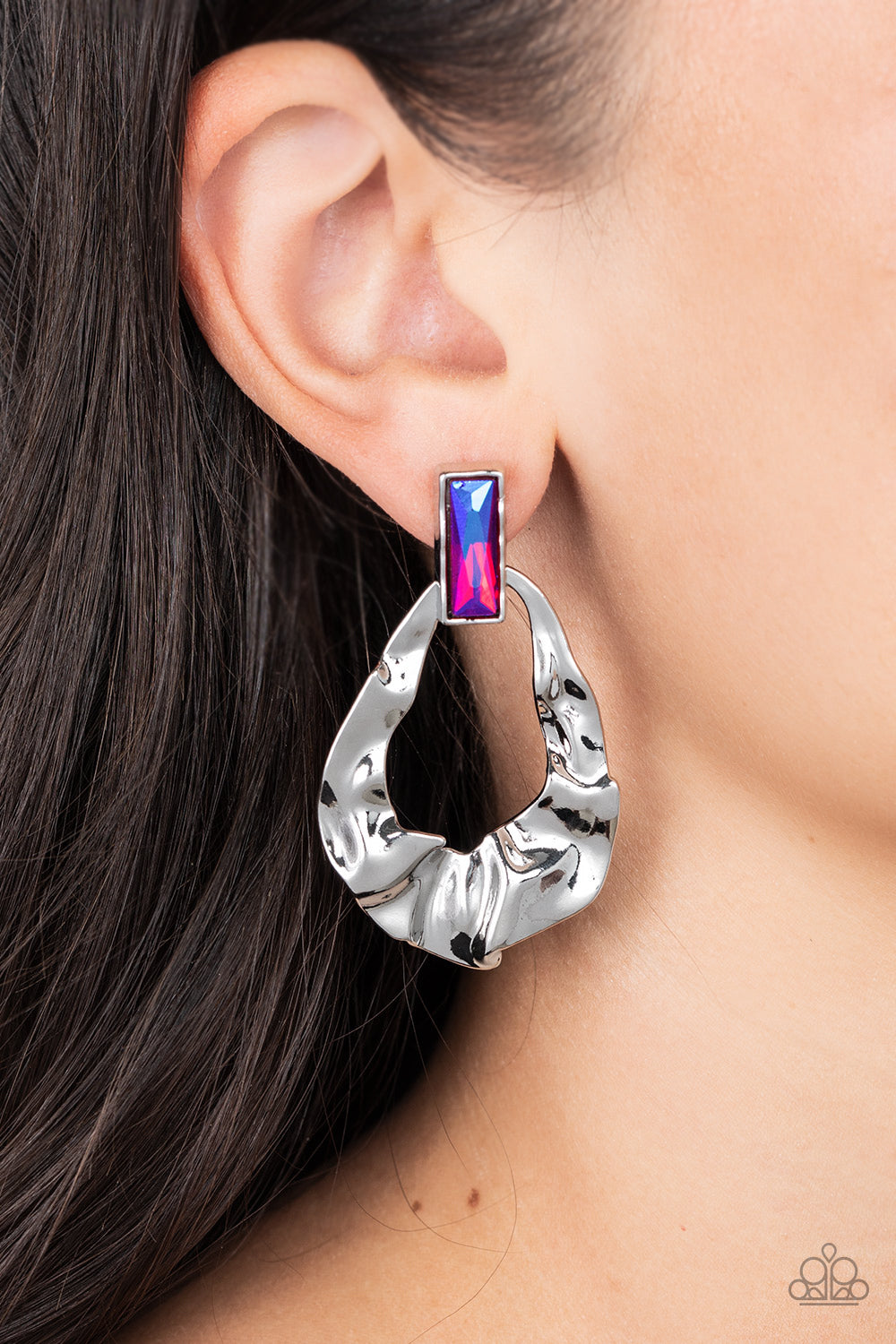 Folds of warped silver delicately gather into an edgy teardrop at the bottom of an emerald cut iridescent pink rhinestone. Earring attaches to a standard post fitting. Due to its prismatic palette, color may vary.  Sold as one pair of post earrings.