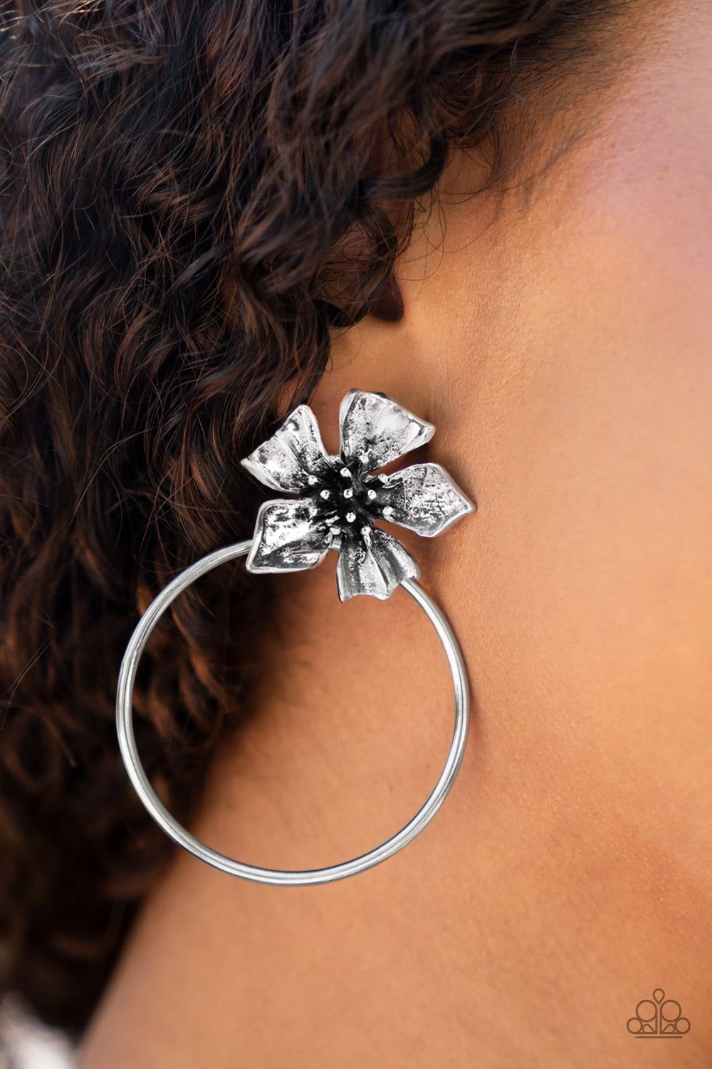 Featuring lifelike textures, a shimmery silver buttercup blooms atop an oversized silver hoop for a whimsical allure. Earring attaches to a standard post fitting.  Sold as one pair of post earrings.