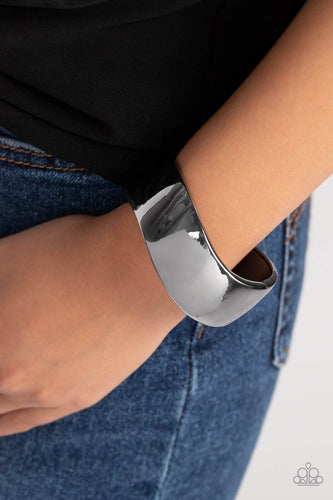 A thick band of gunmetal wraps around the wrist in a dramatic display. As the edges of the band curve into subtle waves, the high sheen finish creates a blinding display of intense sheen that demands attention. Features a hinged closure.  Sold as one individual bracelet.