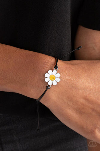 Held together and centered within soft black cording, a single daisy charm rests. Featuring a silver smiley face in its yellow center, this single flower provides a fashionably, minimalistic statement around the wrist. Features an adjustable sliding knot closure.  Sold as one individual bracelet.