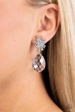 Load image into Gallery viewer, An explosion of radiating silver bars is topped with a sprinkle of iridescent rhinestones, creating a stellar anchoring point. Swinging below the starburst, an oversized, clear teardrop with a light-catching, faceted surface is wrapped in a textured border of silver, adding stunning dimension and refinement to the cosmic combination. Earring attaches to a standard post fitting. Due to its prismatic palette, color may vary. Sold as one pair of post earrings.

