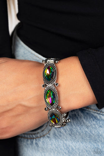 Glittery oil spill gems are pressed into silver studded, marquise-cut frames, titled on its side. Separated by dainty hematite rhinestones encased in sleek silver frames, the sparkly collection is threaded along elastic stretchy bands for a dramatic look around the wrist. Due to its prismatic palette, color may vary.  Sold as one individual bracelet.