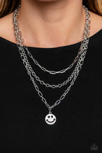 Load image into Gallery viewer, A trio of silver paperclip, classic, and oval link chains coalesces down the neckline for a monochromatic masterpiece. Strung on the lowermost oval link chain, a silver smiley face pendant, with a star mimicking a wink for one of its eyes, stands out and reflects light in every direction for a statement finish. Features an adjustable clasp closure.     Sold as one individual necklace. Includes one pair of matching earrings.
