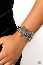 Load image into Gallery viewer, Strung along elastic stretchy bands, a trio of silver and textured silver beads and accents wrap around the wrist. Featured atop the beaded collection, an oversized silver butterfly, with intricate details, is sprinkled with dainty white rhinestones across its wings and body, for a dramatically dazzling finish.  Sold as one individual bracelet.
