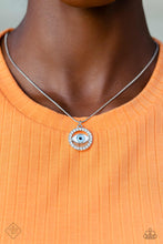Load image into Gallery viewer, A light blue eye pendant is accented by silver edging and then wrapped in a circular border of brilliant white rhinestones. The sparkling charm slides effortlessly along a dainty snake chain, adding eye-catching movement to the design. Features an adjustable clasp closure. Includes one pair of matching earrings.
