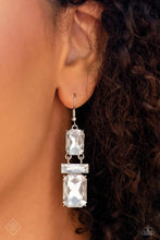 Load image into Gallery viewer, Two oversized emerald-cut gems sparkle unapologetically, increasing in size as they fall from the ear. A white gem bar, featuring sharp faceted surfaces, lays perpendicular to the blinding emerald-cut gems, separating the two and emphasizing their hinged movement. Earring attaches to a standard fishhook fitting.
