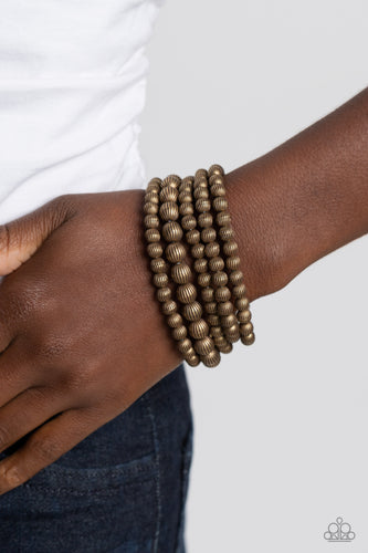 Gritty strands of brass beads etched in linear patterns wrap around the wrist on stretchy bands. One strand of the linear brass beads features bigger beads than the rest of the collection for an earthy contrast to the design.  Sold as one set of five bracelets.