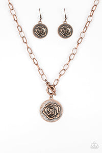 Embossed in a whimsical rosebud pattern, a shimmery copper frame swings below the collar for a casual look. Features a toggle closure. Sold as one individual necklace. Includes one pair of matching earrings.