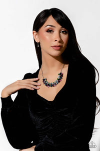 Featuring pronged silver fittings, a sparkly series of marquise-cut rhinestones in varying sizes and opacities are splashed in hues of purple, blue, light blue, baby pink, pink, and green as they fan out below the collar for a vibrant statement. Fuchsia and white round gems in varying sizes sporadically cluster around the marquise-cuts for additional shimmer in the geometric, refined display.  Sold as one individual necklace. Includes one pair of matching earrings.
