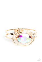 Load image into Gallery viewer, Featured in the center of airy, shiny gold bands, an oversized, faceted iridescent oval gem rests atop the wrist for a dazzling pop of color. Warped, shiny gold rings seemingly float around the sparkly gem for a whimsical finish. Features a hinged closure. Due to its prismatic palette, color may vary.  Sold as one individual bracelet.
