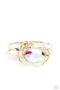 Featured in the center of airy, shiny gold bands, an oversized, faceted iridescent oval gem rests atop the wrist for a dazzling pop of color. Warped, shiny gold rings seemingly float around the sparkly gem for a whimsical finish. Features a hinged closure. Due to its prismatic palette, color may vary.  Sold as one individual bracelet.