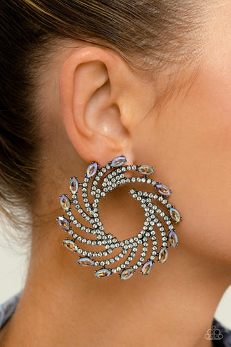 Shimmery strands of silver spin out from an airy center, creating an exaggerated firework-like display at the ear. An explosion of dainty white rhinestones lines the swirls and curves of the shimmery display leading the eye to the collection of colorfully reflective marquise-cut gems at its ends. Each colorfully reflective marquise-cut gem curls around the ear in a clock-like manner, creating additional eye-catching dimension.