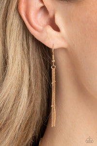 Chains hanging from a gold fish hook earring.