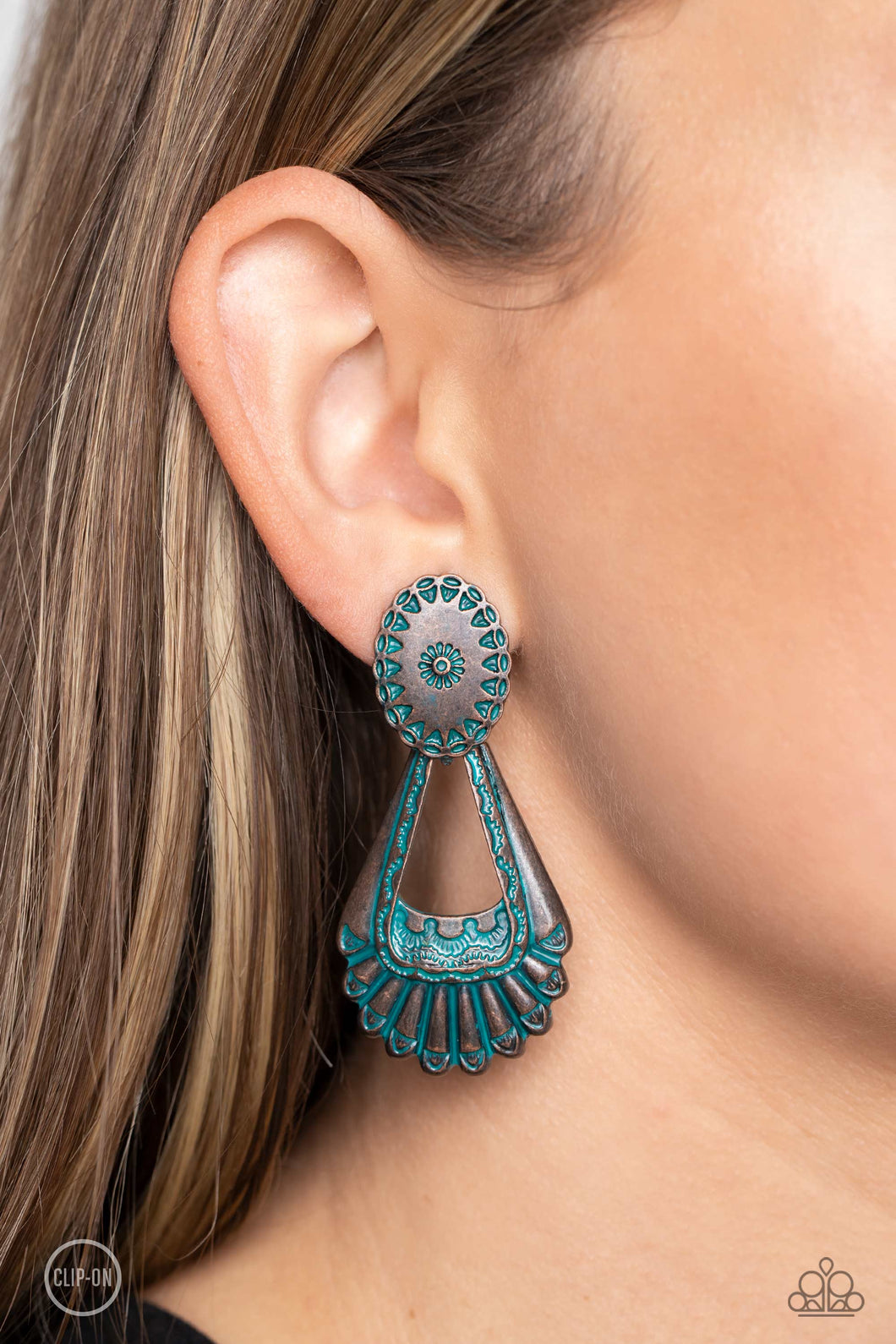 Dangling from a Southwestern-patterned post, a rustic, brass patina frame swings for some aged authenticity below the ear. Feathered details stream from the lower frame for additional artisanal detail. Earring attaches to a standard clip-on fitting.  Sold as one pair of clip-on earrings.