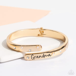 High-sheen gold curves into a hinged closure around the wrist. Featured on the upper curve, dainty pearls and white rhinestones alternate in a zig-zag pattern for a refined shimmer. The lower curve of gold features the stamped word "Grandma" in a curly font with rhinestones and pearls bordering the word for additional elegance. Features a hinged closure.  Sold as one individual bracelet.