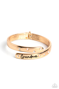 High-sheen gold curves into a hinged closure around the wrist. Featured on the upper curve, dainty pearls and white rhinestones alternate in a zig-zag pattern for a refined shimmer. The lower curve of gold features the stamped word "Grandma" in a curly font with rhinestones and pearls bordering the word for additional elegance. Features a hinged closure.  Sold as one individual bracelet.