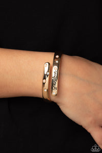 High-sheen gold curves into a hinged closure around the wrist. Featured on the upper curve, dainty pearls and white rhinestones alternate in a zig-zag pattern for a refined shimmer. The lower curve of gold features the stamped word "Grandma" in a curly font with rhinestones and pearls bordering the word for additional elegance. Features a hinged closure.  Sold as one individual bracelet.