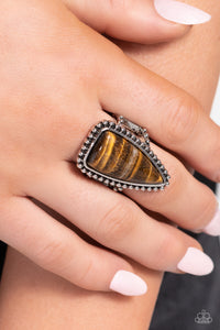 An oversized tiger's eye triangle stone is nestled inside a silver frame studded and embellished in antiqued silver details for an authentic finish. Features a stretchy band for a flexible fit. As the stone elements in this piece are natural, some color variation is normal.  Sold as one individual ring.