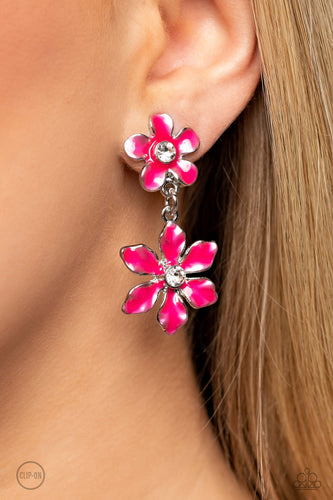 A hot pink transparent flower with pinched petals blooms around a glittery white gem center. The large flower swings from a second transparent hot pink flower, featuring a smaller size with fanned-out petals encircling a glittery white gem center. The elements combine to create a whimsical lure rich in character. Earring attaches to a standard clip-on fitting.  Sold as one pair of clip-on earrings.