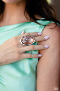 Featuring a refracted shimmer, an oversized oval-cut, glossy orange gem sparkles from an asymmetrical silver frame for an edgy statement piece atop the finger. Features a stretchy band for a flexible fit.  Sold as one individual ring.
