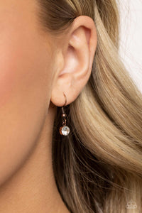 Small rhinestone hanging from a copper fish hook earring.