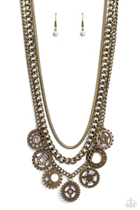 Brass gear pendants with varying textures, details, sizes, and a dusting of white rhinestones, swing from a thick brass curb chain, creating a steampunk-like fringe. A brass snake chain and an additional brass curb chain combine with the grungy, industrial display for additional sheen and attitude. Features an adjustable clasp closure.  Sold as one individual necklace. Includes one pair of matching earrings.
