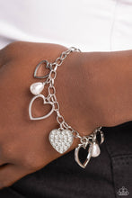 Load image into Gallery viewer, Glistening silver heart silhouettes, white potato pearls, and a white rhinestone-encrusted silver heart frame dangle from a classic silver chain link around the wrist, resulting in a romantic fringe. Features an adjustable clasp closure.  Sold as one individual bracelet
