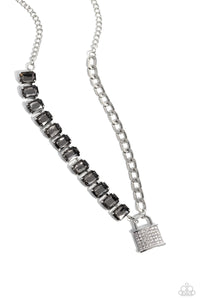 Infused on a classic silver chain, a strand of thick silver curb chain, and a collection of exaggerated, smoky radiant-cut gems in silver pronged fittings combine to create a collision of industrial color around the neckline. An oversized silver lock charm, embossed in white rhinestones, dangles from the gritty display for a touch of soft glitz to the design. Features an adjustable clasp closure.  Sold as one individual necklace. Includes one pair of matching earrings.