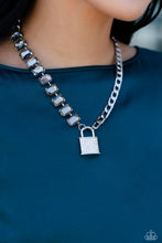 Load image into Gallery viewer, Infused on a classic silver chain, a strand of thick silver curb chain, and a collection of exaggerated, smoky radiant-cut gems in silver pronged fittings combine to create a collision of industrial color around the neckline. An oversized silver lock charm, embossed in white rhinestones, dangles from the gritty display for a touch of soft glitz to the design. Features an adjustable clasp closure.  Sold as one individual necklace. Includes one pair of matching earrings.
