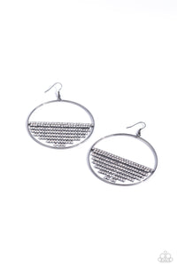 A curtain of white rhinestones is stretched between the edges of a skinny, oversized gunmetal hoop, creating a shimmering display. The rhinestones taper towards the center as they sway and cascade, adding sparkly movement for a fierce industrial finish. Earring attaches to a standard fishhook fitting.  Sold as one pair of earrings.