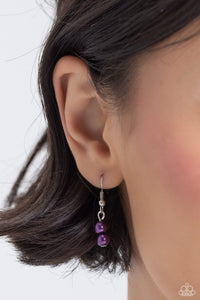 Two purple beads hanging from a silver fish hook earring.