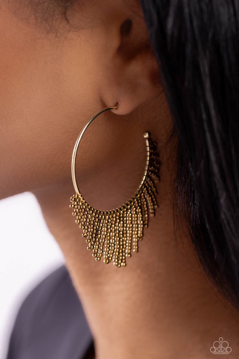 Cascading strands of brass seed beads stream out from the bottom of a classic brass hoop, resulting in a flirtatiously tasseled look. Earring attaches to a standard post fitting. Hoop measures approximately 1 1/2