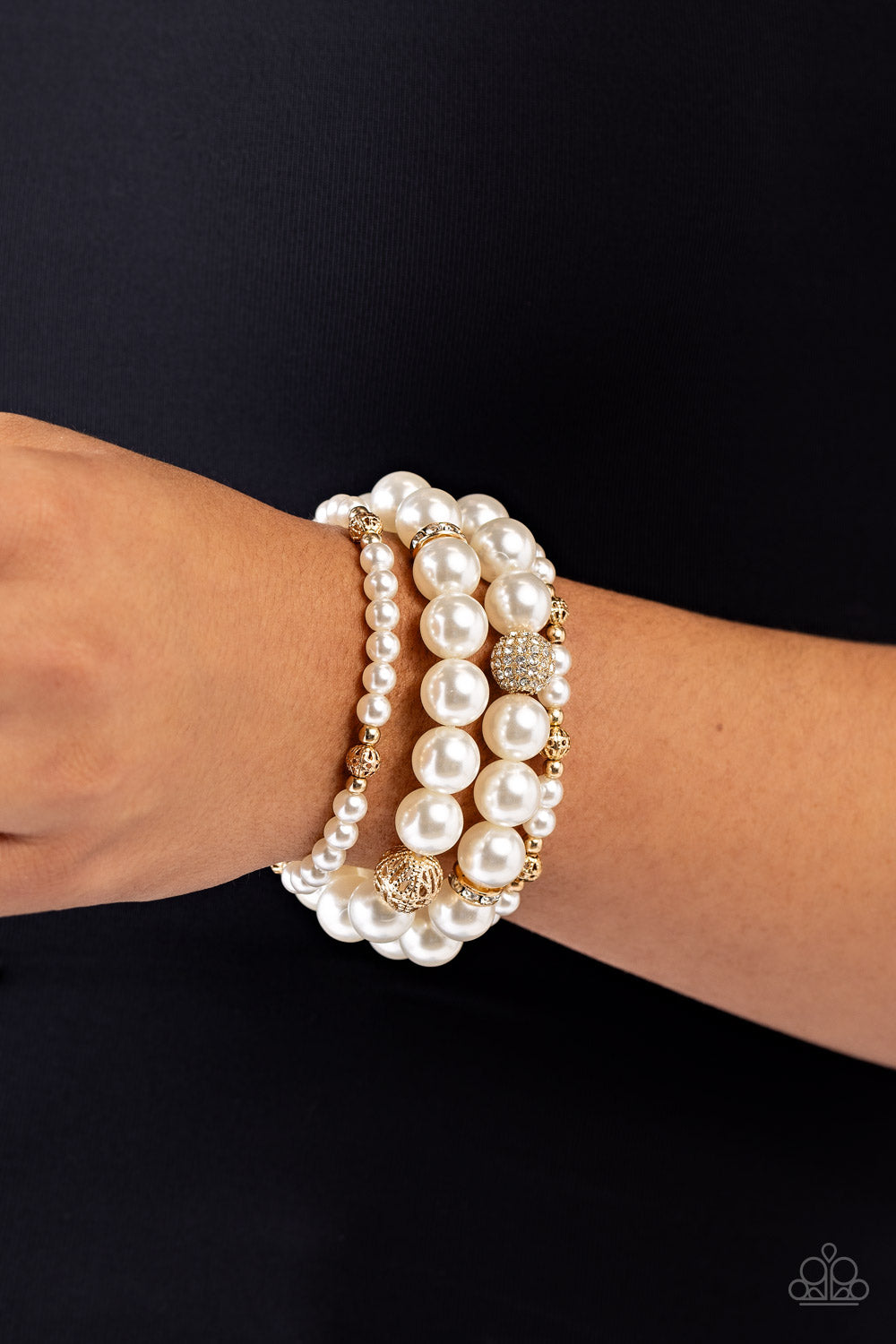Infused with white rhinestone-encrusted gold beads, white rhinestone-encrusted discs, and textured gold beads, a bubbly collection of mismatched white pearls are threaded along stretchy bands around the wrist for a vintage-inspired layered look.  Sold as one set of four bracelets.