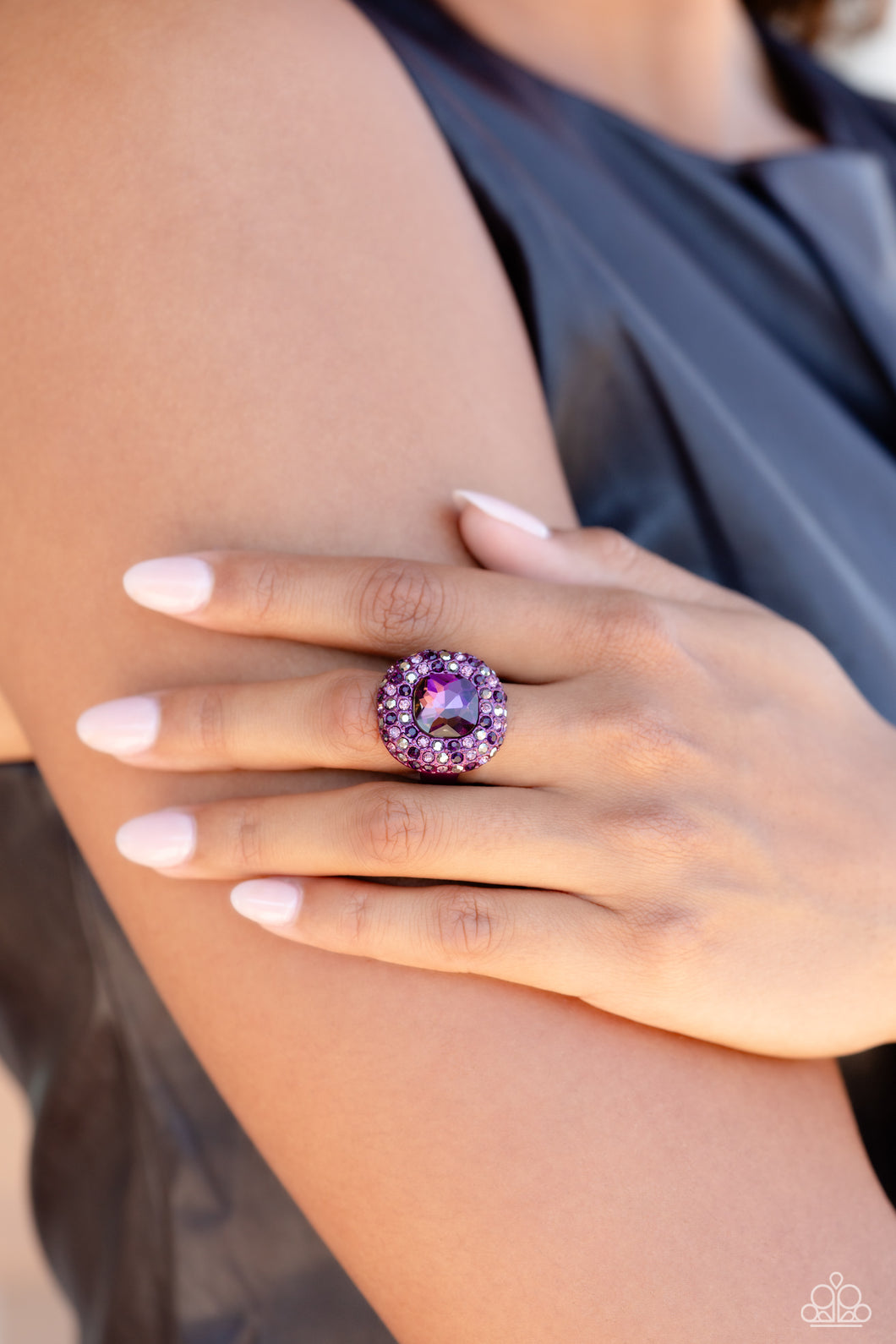 Featuring a regal square cut, an oversized plum gem nestles inside a rounded square purple metallic frame encrusted in glassy hematite, purple, and amethyst rhinestones for a dramatically glamorous look. Features a dainty stretchy band for a flexible fit.  Sold as one individual ring.