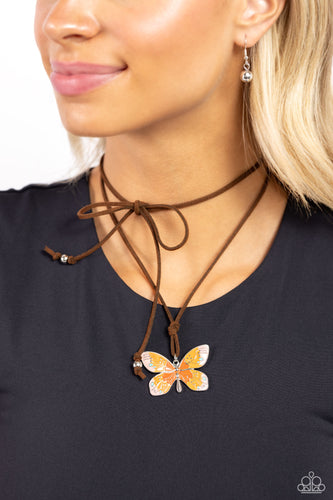Featuring an ombre effect of baby pink to coral to Burnt Orange and accents of tiffany, a vivacious oversized butterfly flutters at the bottom of a knotted lengthened strand of brown suede for a wanderlust statement. Features an adjustable sliding bead closure.  Sold as one individual necklace. Includes one pair of matching earrings.