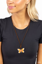 Load image into Gallery viewer, Featuring an ombre effect of baby pink to coral to Burnt Orange and accents of tiffany, a vivacious oversized butterfly flutters at the bottom of a knotted lengthened strand of brown suede for a wanderlust statement. Features an adjustable sliding bead closure.  Sold as one individual necklace. Includes one pair of matching earrings.
