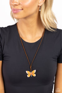 Featuring an ombre effect of baby pink to coral to Burnt Orange and accents of tiffany, a vivacious oversized butterfly flutters at the bottom of a knotted lengthened strand of brown suede for a wanderlust statement. Features an adjustable sliding bead closure.  Sold as one individual necklace. Includes one pair of matching earrings.