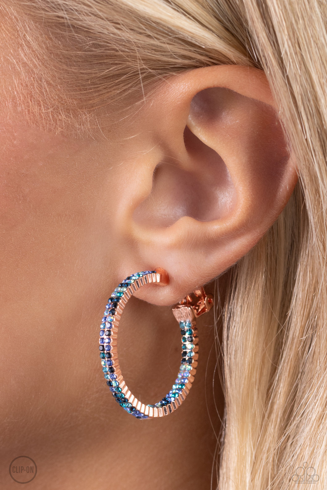 The front half and lower inner curve of a textured shiny copper hoop are encrusted in dazzling ombré shades of blue for a flawless look. Earring attaches to a standard clip-on fitting. Hoop measures approximately 1