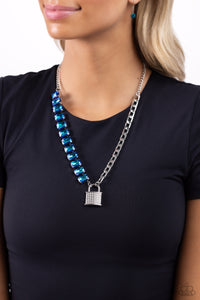Infused on a classic silver chain, a strand of thick silver curb chain, and a collection of exaggerated, blue UV radiant-cut gems in silver pronged fittings combine to create a collision of industrial color around the neckline. An oversized silver lock charm, embossed in white rhinestones, dangles from the gritty display for a touch of soft glitz to the design. Features an adjustable clasp closure.  Sold as one individual necklace. Includes one pair of matching earrings.