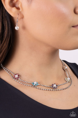 Featuring silver square fittings, white rhinestones cascade into two layers below the collar adding glitzy movement to the sparkling centerpiece. Infused along the uppermost chain, a glitzy collection of pearl-dotted flowers with rose, blue, amethyst, yellow, and peachy rhinestone petals creates a splash of whimsical color. Features an adjustable clasp closure.   Featured inside The Preview at Made for More! Sold as one individual necklace. Includes one pair of matching earrings.