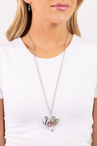 Featuring blue, fuchsia, olive, and rose rhinestones, the word "LOVE" floats inside an oversized, airy heart-shaped frame as it sways from a lengthened silver chain for a Valentine's-inspired centerpiece. Features an adjustable clasp closure. Sold as one individual necklace. Includes one pair of matching earrings. 