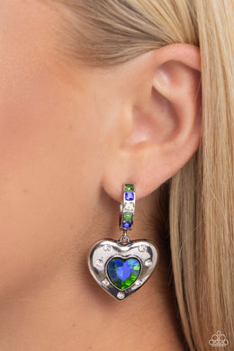 Featuring a UV shimmer, a green/blue heart gem is pressed into an antiqued silver heart frame adorned in white rhinestones. The antiqued heart sways from the bottom of a thick silver hoop encrusted in square green, blue, and white gems resulting in a whimsical fashion. Earring attaches to a standard post fitting. Hoop measures approximately 3/4