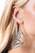 Load image into Gallery viewer, Splashed in a metallic silver hue, an oversized butterfly wing with airy cutout details dangles from the ear, creating a whimsically colorful sight. Earring attaches to a standard fishhook fitting.  Sold as one pair of earrings.
