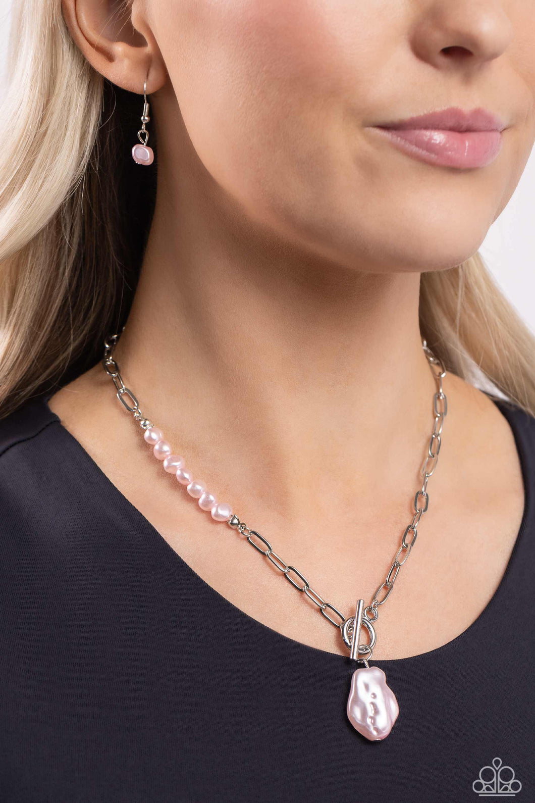 Featuring an elegant lariat closure, an oversized, baroque baby pink pearl cascades from the bottom of a silver paperclip chain for a refined fashion. Dainty, glossy baroque baby pink pearl beads are infused along one side of the silver chain for an additional touch of abstract sheen to the charming design.  Sold as one individual necklace. Includes one pair of matching earrings.