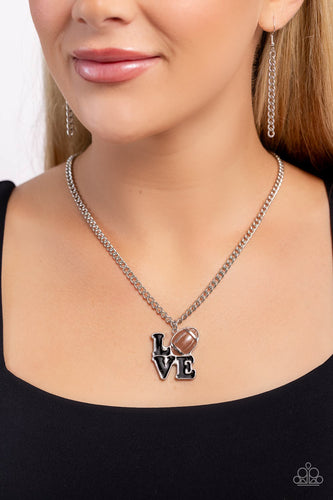 Gliding along a classic silver chain, a black-painted word pendant spells out the word 